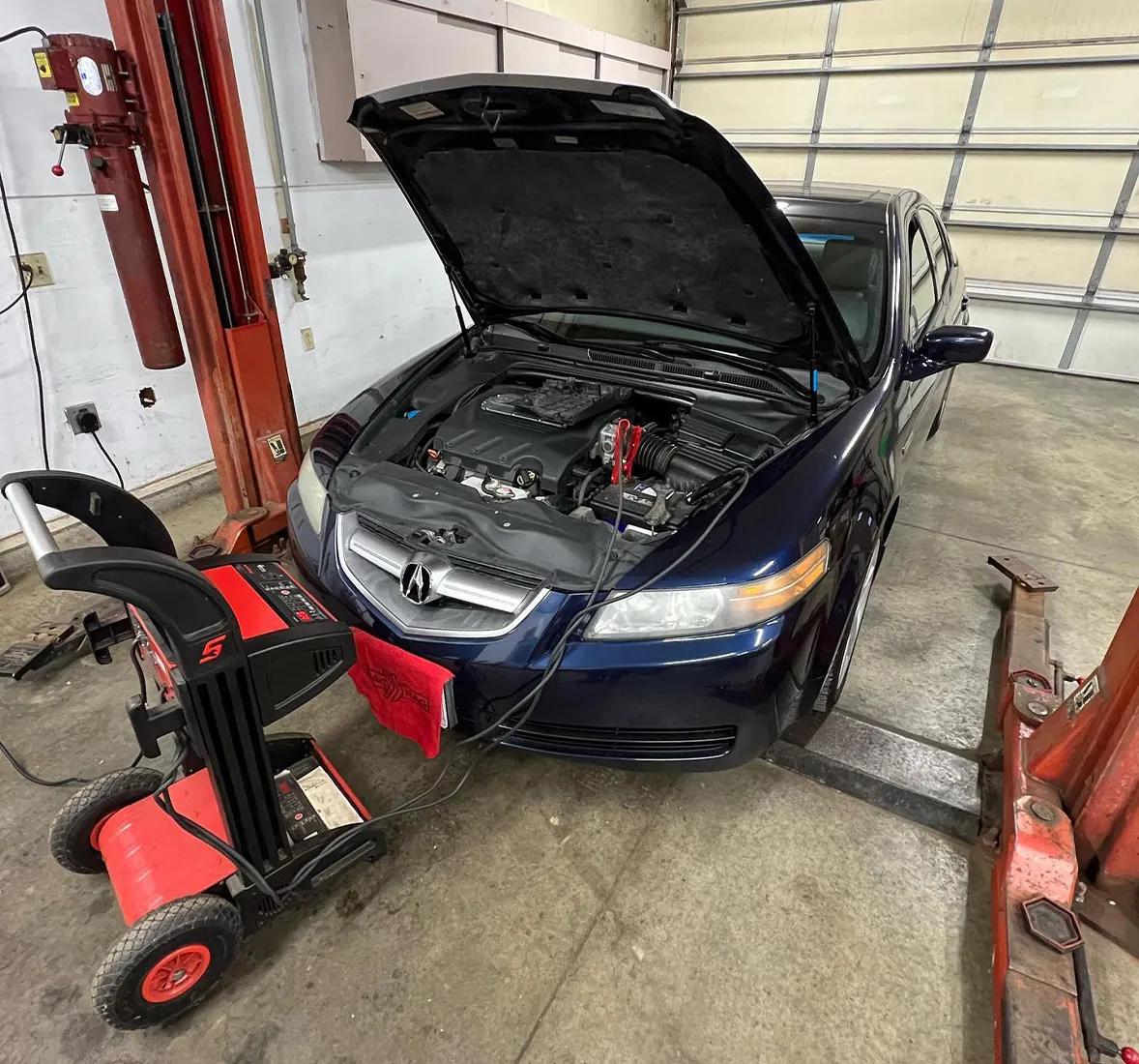 Image of a blue Acura car with battery being checked and serviced. Concept image of Acura repair at Enright Automotive.