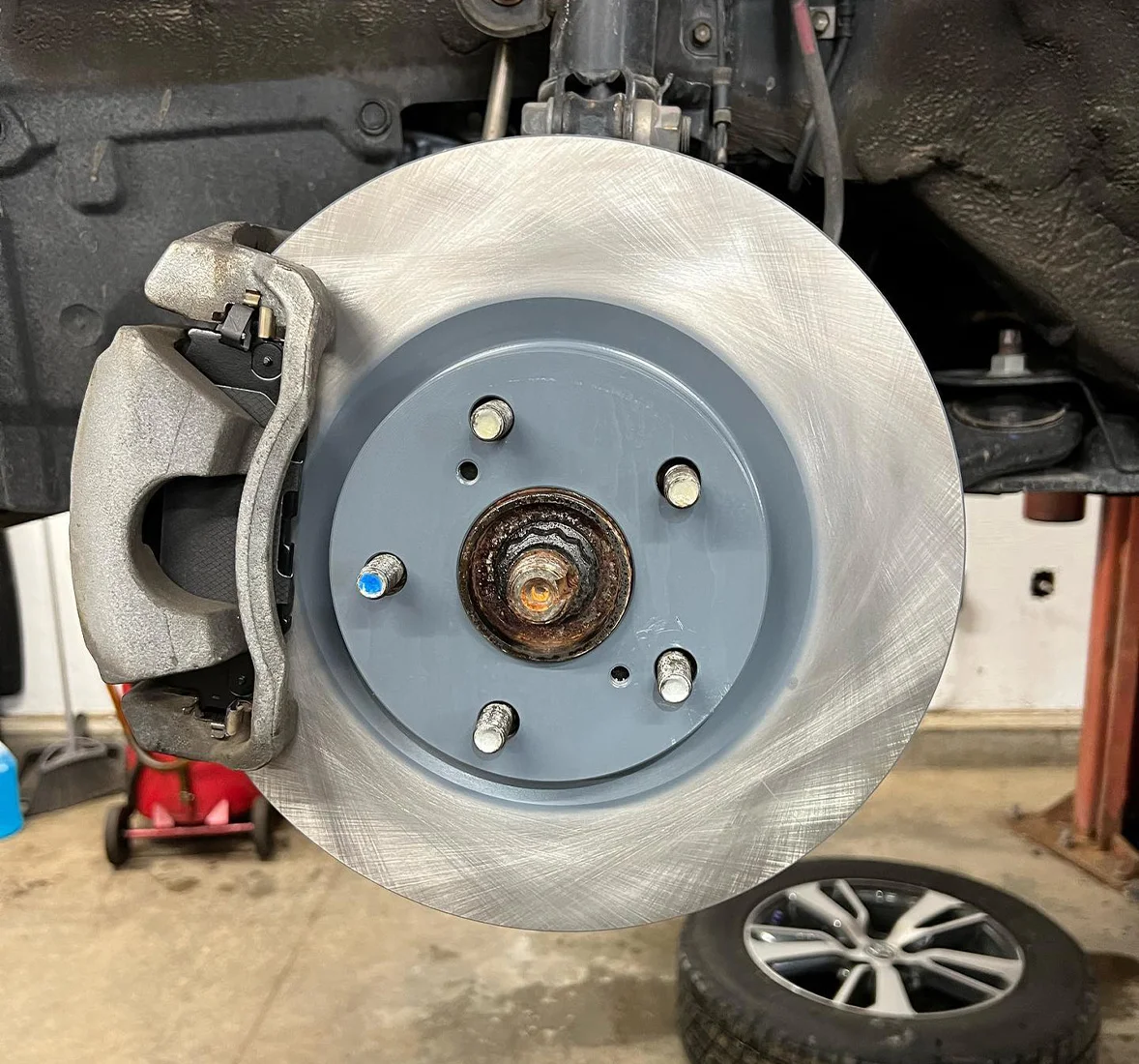 Closeup image of brake rotor, brak caliper, brake pad, and a tire. Concept image of brake repair at Enright Automotive.