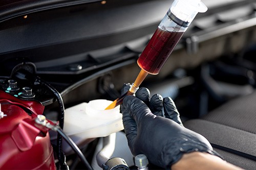 An auto technician changing brake fluid. Concept image of “Is Brake Fluid Flush Really Necessary?” | Enright Automotive in Alexandria, OH.