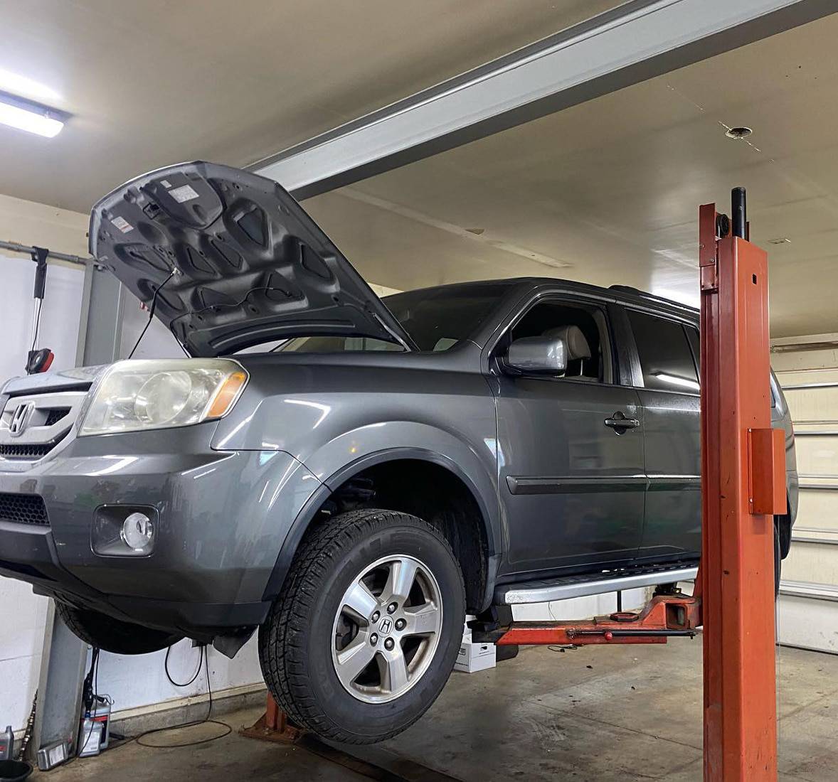 Japanese Auto Repair in Pataskala, OH | Honda & Acura Specialists | Enright Automotive. Image of gray honda piolet on shop lift with hood open for repairs.