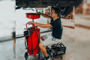 Preventative maintenance in Alexandria, OH, at Enright Automotive. Image of a technician performing an oil change beneath a vehicle using professional fluid extraction equipment to maintain engine performance, improve reliability, and extend vehicle life through routine maintenance.