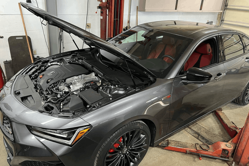 Auto repair shop warranty, auto repair in Alexandria, OH at Enright Automotive. Image of a gray Acura sedan with the hood open inside the repair shop, showing the engine bay during service.